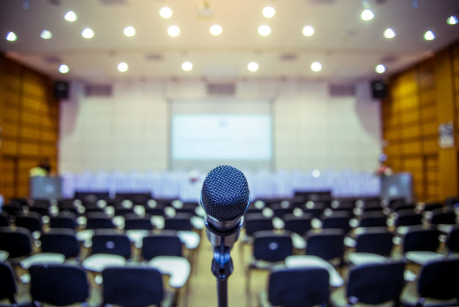 Microphone over the Abstract blurred photo of conference hall or seminar room background